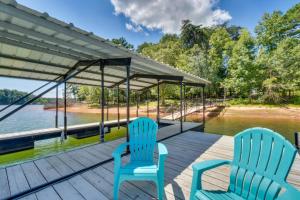 twee blauwe stoelen op een steiger naast het water bij Spacious Lake Hartwell Home with Private Boat Dock! in Anderson