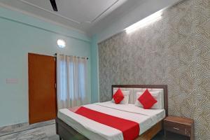 Super OYO Flagship Siddharth Inn في لاكناو: غرفة نوم عليها سرير ومخدات حمراء