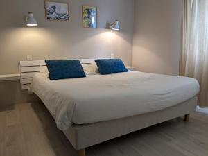 ein Schlafzimmer mit einem großen Bett mit blauen Kissen in der Unterkunft Fuzei Hôtel Lorient-Lanester in Lanester