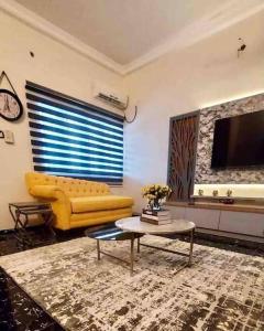 a living room with a yellow couch and a table at Peniel Place in Makurdu