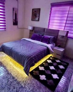 a bedroom with a bed with purple sheets and purple pillows at Peniel Place in Makurdu