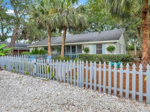 a white picket fence in front of a house at Salt Palms Cottage in Tybee Island