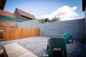 a patio with two green chairs and a fence at CosyVilla - Spa Sauna Hammam 