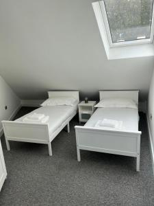 two white beds in a room with a window at 2 bedroom flat in London