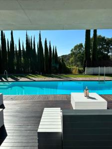 una piscina con due panchine bianche accanto alla piscina di Villa Moderna Exclusiva con Jardín Privado La Villa de Sevilla a Guillena
