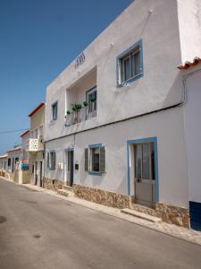 un bâtiment blanc sur le côté d'une rue dans l'établissement Casa Olívia, à Carrapateira