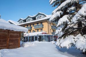 a building with snow on the ground in front of it at Alpinhotel Maistatt in Schladming
