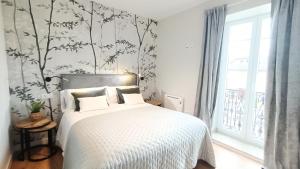 a bedroom with a white bed with a tree wallpaper at Casa da Americana II in Boqueijón