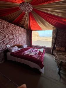 a bedroom with a bed in a tent with a window at Serenity Camp in Wadi Rum