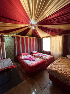 two beds in a room with red curtains at Serenity Camp in Wadi Rum +29 photos