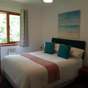 a bedroom with a large white bed with green pillows at Hawthorn Lodge in Fort William