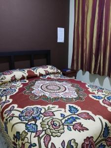 a bed with a colorful comforter on top of it at Lolitas Alojamiento Quillacollo in Cochabamba