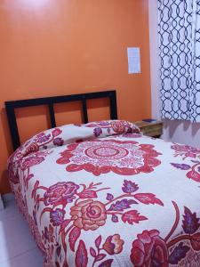 a bed with a red and white blanket with flowers at Lolitas Alojamiento Quillacollo in Cochabamba