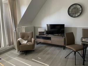 a living room with a flat screen tv and two chairs at Haus Südwind in Büsum