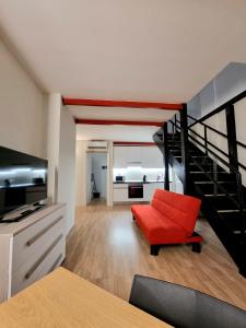 a living room with a red chair and a staircase at Comodo Loft Centro a Jesolo Lido - Free Beach place a 1 minuto!!! in Lido di Jesolo