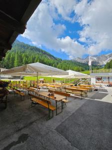 a group of picnic tables with white umbrellas at Die Schlickeralm in Telfes im Stubai