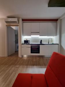 een woonkamer met een rode bank en een keuken bij Comodo Loft Centro a Jesolo Lido - Free Beach place a 1 minuto!!! in Lido di Jesolo