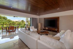 a living room with a white couch and a television at Romantic getaway next to the beach in Cancún