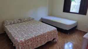 a room with two beds and a small bed and a window at Lar doce lar em Paraty in Paraty