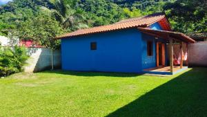 a blue house with a green lawn in front of it at Lar doce lar em Paraty in Paraty