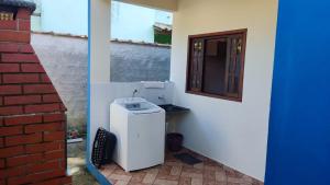 a small refrigerator sitting next to a wall with a window at Lar doce lar em Paraty in Paraty