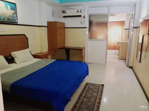 a bedroom with a blue bed and a kitchen at GRG Swagat Bhubneshwar in Bhubaneshwar