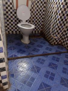 a bathroom with a toilet with a blue tile floor at GRG Swagat Bhubneshwar in Bhubaneshwar