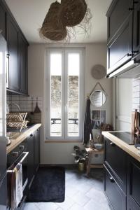 une cuisine avec des armoires noires et une fenêtre dans l'établissement Appartement d'architecte - Puteaux Centre, à Puteaux