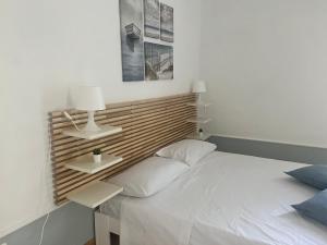 a bedroom with a white bed with a wooden headboard at Mediterraneo Apartment in Ercolano