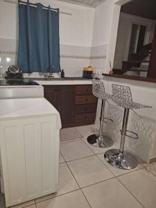 eine Küche mit einer Theke und 2 Stühlen darin in der Unterkunft La Bell'appart Ibis rouge in Sinnamary