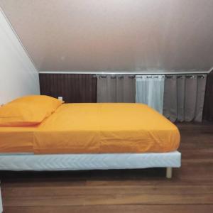 Bett mit orangefarbener Tagesdecke in einem Zimmer in der Unterkunft La Bell'appart Ibis rouge in Sinnamary