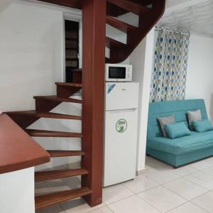 sala de estar con escalera y sofá azul en La Bell'appart Ibis rouge, en Sinnamary