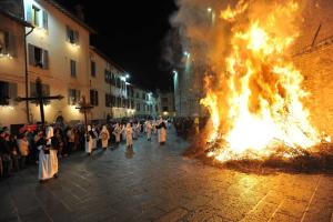 un grupo de personas de pie alrededor de un fuego en una calle en Casa Stefy Gubbio Centro, en Gubbio