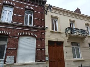 a brick building with a red door and a balcony at Le Mc Fly in Hénin-Beaumont