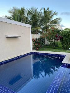 une piscine de carrelage bleu avec un bâtiment et des palmiers dans l'établissement Apartamento 2 quartos a 300m da Praia, à Santa Cruz Cabrália