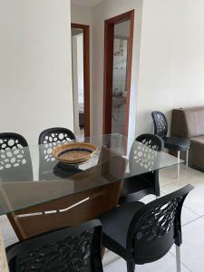uma mesa de vidro com cadeiras pretas e uma tigela. em Apartamento 2 quartos a 300m da Praia em Santa Cruz Cabrália