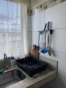 - un évier de cuisine avec un plateau noir sur un comptoir dans l'établissement Apartamento 2 quartos a 300m da Praia, à Santa Cruz Cabrália