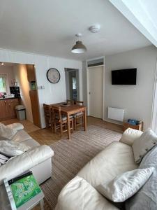 a living room with a couch and a table with a clock at Cosy Chalet for Snowdonia in Caernarfon