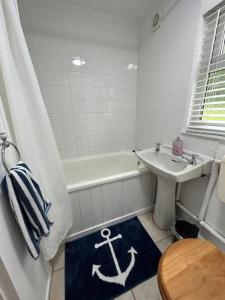 a bathroom with a sink and a bath tub with a anchor rug at Cosy Chalet for Snowdonia in Caernarfon