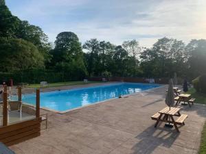 a large swimming pool with two picnic tables and chairs at Cosy Chalet for Snowdonia in Caernarfon