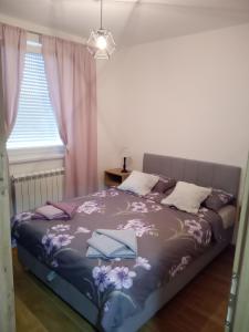 1 dormitorio con 1 cama grande con flores púrpuras en Sara Lux, en Lukavica
