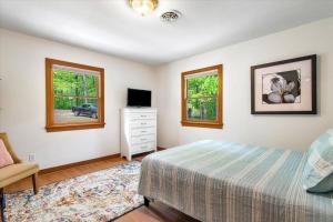 a bedroom with a bed and a tv and windows at Serenity in the Suburbs: Your Gorgeous RVA Getaway in Richmond