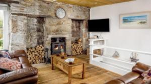 a living room with a stone wall with a fireplace at Boatsman's Cottage- sleeps 4- Garage- Mousehole in Mousehole