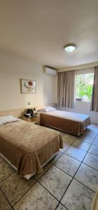 a hotel room with two beds and a window at GoldMen Business Londrina in Londrina +20 photos