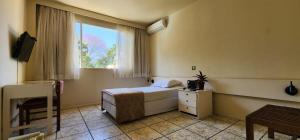 a small bedroom with a bed and a window at GoldMen Business Londrina in Londrina