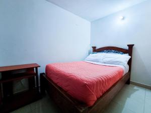 a bedroom with a bed with a red blanket and a table at Hostal Casa Doña Eva -Rionegro Antioquia in Rionegro