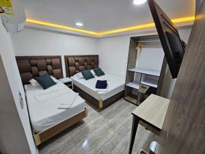 Habitación pequeña con 2 camas y TV. en Hostel Boutique Nido de Loros, en Medellín