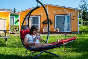 a woman and a baby sitting on a swing at Navigateur Ste-Luce in Sainte-Luce-sur-Mer