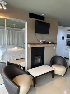 a living room with two chairs and a fireplace at LINDABAYPLAYA STUDIO in Mar de las Pampas