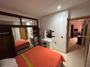 um quarto com uma cama laranja e um espelho em Inara Appartement em Tetouan
